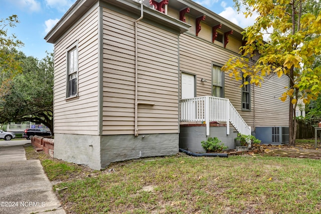 view of side of property featuring cooling unit and a yard