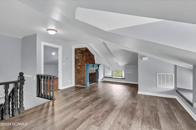 bonus room featuring a brick fireplace, vaulted ceiling, and hardwood / wood-style floors