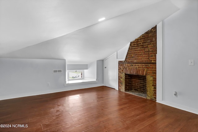 unfurnished living room featuring lofted ceiling, a brick fireplace, and hardwood / wood-style flooring