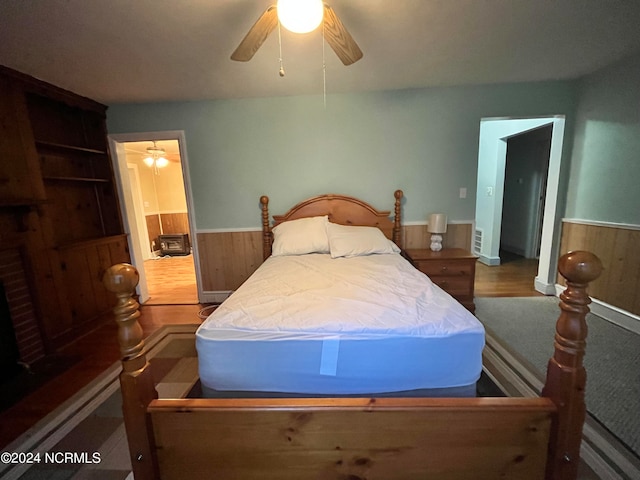 bedroom featuring ceiling fan, wainscoting, and wooden walls