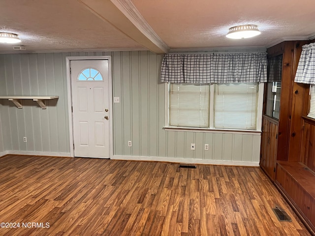 entryway featuring ornamental molding, visible vents, a textured ceiling, and wood finished floors