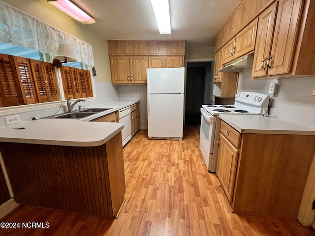 kitchen with a peninsula, white appliances, a sink, light countertops, and light wood finished floors