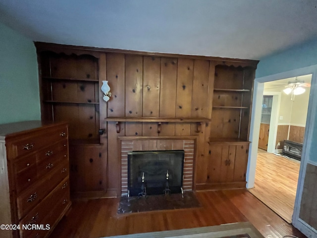 unfurnished living room featuring a wainscoted wall, a fireplace, and wood finished floors