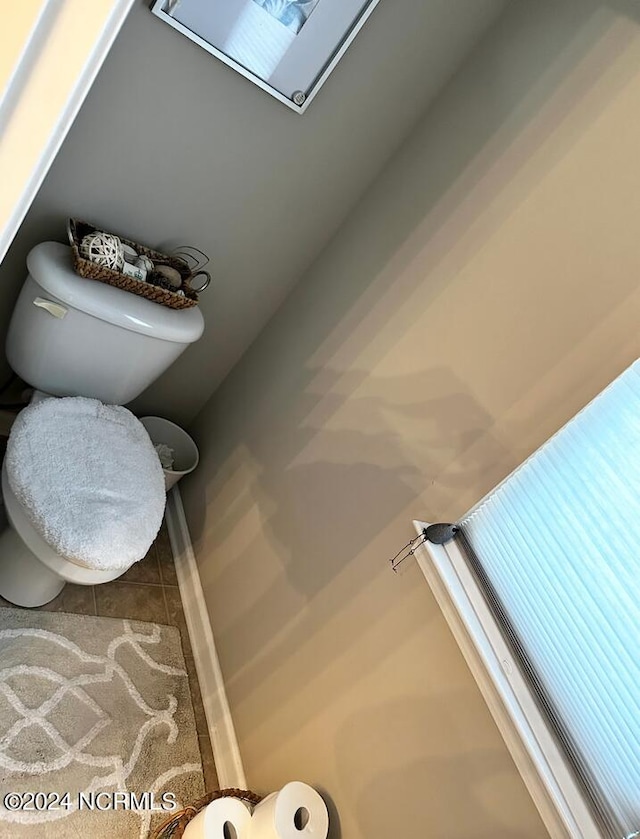 bathroom with tile patterned flooring, a skylight, and toilet