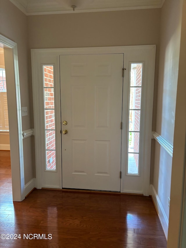 entrance foyer featuring crown molding and dark wood-type flooring