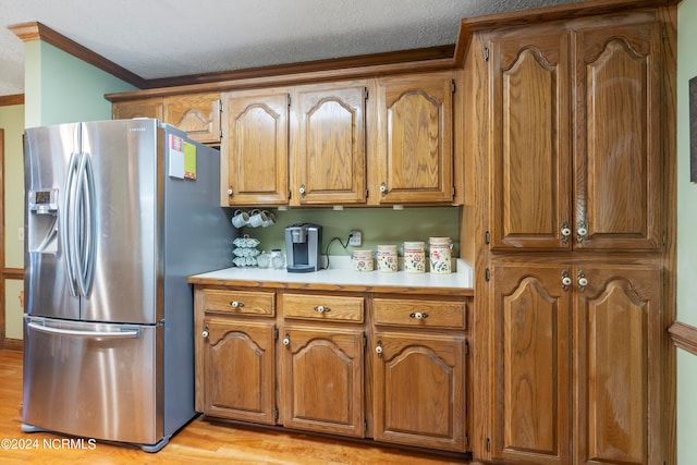 kitchen featuring a textured ceiling, stainless steel refrigerator with ice dispenser, light hardwood / wood-style floors, and crown molding