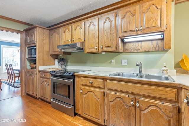 kitchen featuring appliances with stainless steel finishes, a textured ceiling, crown molding, light wood-type flooring, and sink