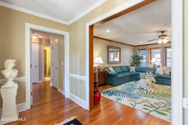 living room with a textured ceiling, ornamental molding, hardwood / wood-style floors, and ceiling fan