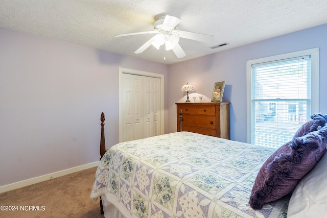 carpeted bedroom with ceiling fan, a textured ceiling, and a closet