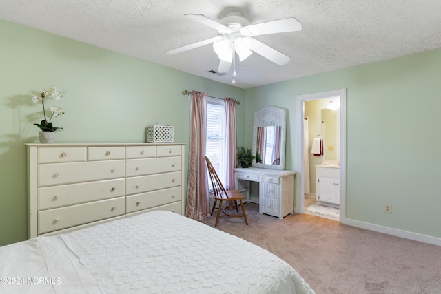 bedroom featuring light carpet, ceiling fan, ensuite bathroom, and a textured ceiling