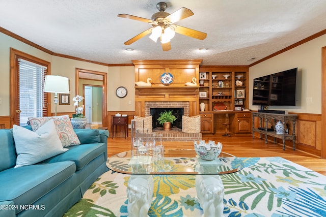 living room featuring a brick fireplace, light hardwood / wood-style floors, ceiling fan, and a textured ceiling