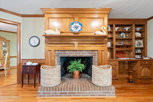 living room featuring a textured ceiling, crown molding, a fireplace, and light hardwood / wood-style flooring