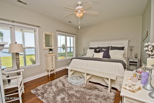 bedroom featuring multiple windows, dark hardwood / wood-style floors, and ceiling fan