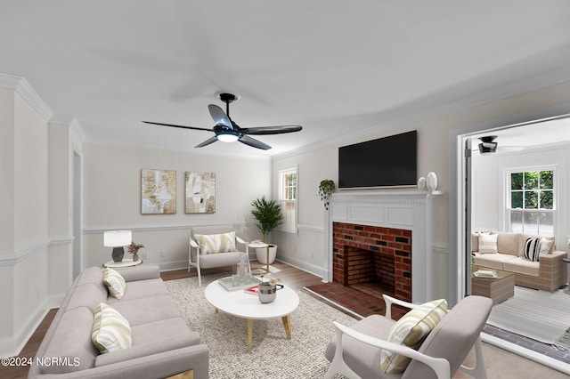 living room featuring a brick fireplace, light hardwood / wood-style flooring, crown molding, and ceiling fan