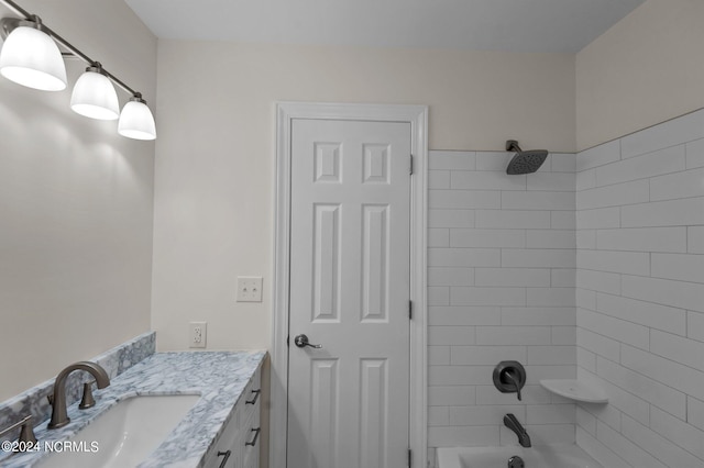 bathroom with tiled shower / bath combo and vanity