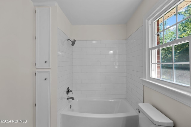 bathroom with tiled shower / bath combo and toilet