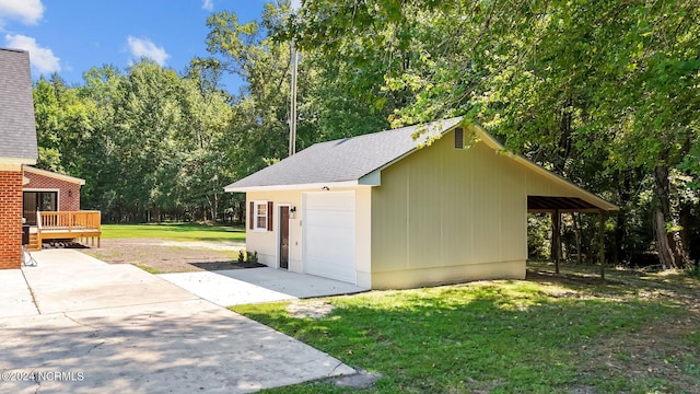 view of outbuilding featuring a garage, a lawn, and a carport