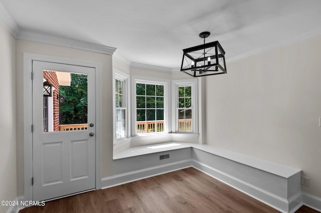 entryway with wood-type flooring, ornamental molding, and a chandelier