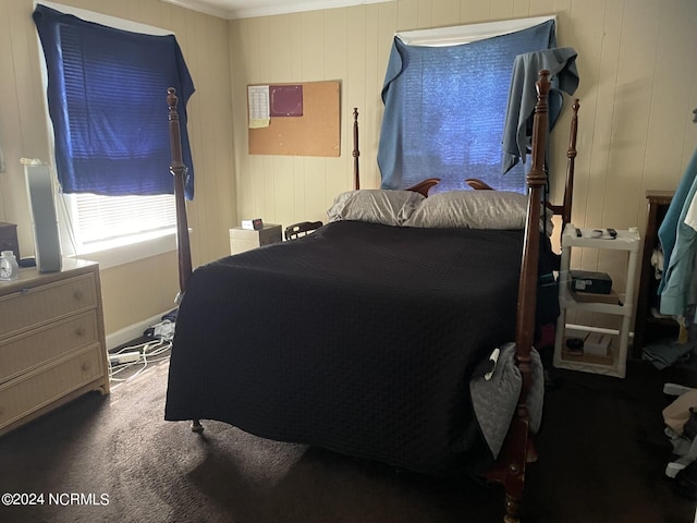 bedroom featuring carpet floors, crown molding, and wood walls