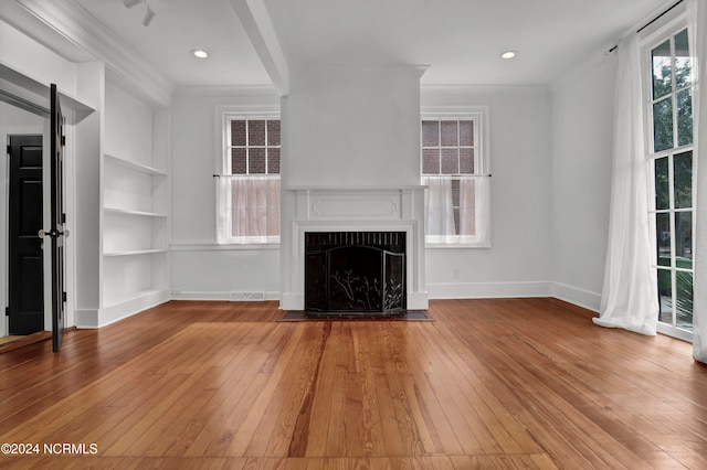 unfurnished living room with light hardwood / wood-style floors, ornamental molding, a fireplace, and built in shelves