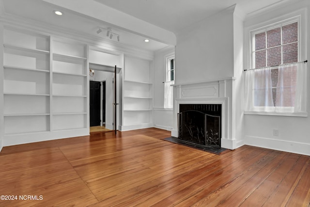 unfurnished living room featuring built in shelves and light wood-type flooring