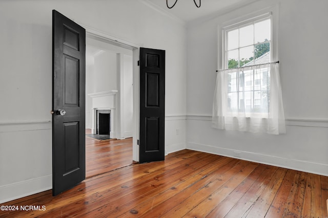 spare room featuring crown molding, wood-type flooring, and an inviting chandelier