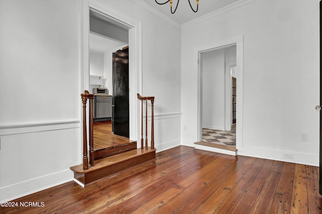 interior space with wood-type flooring, ornamental molding, and an inviting chandelier