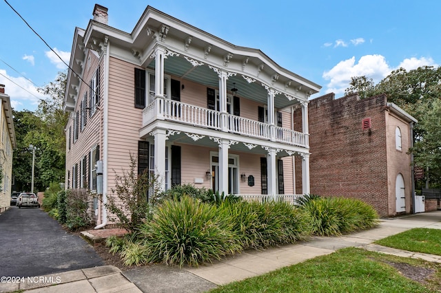 italianate home featuring a balcony and covered porch