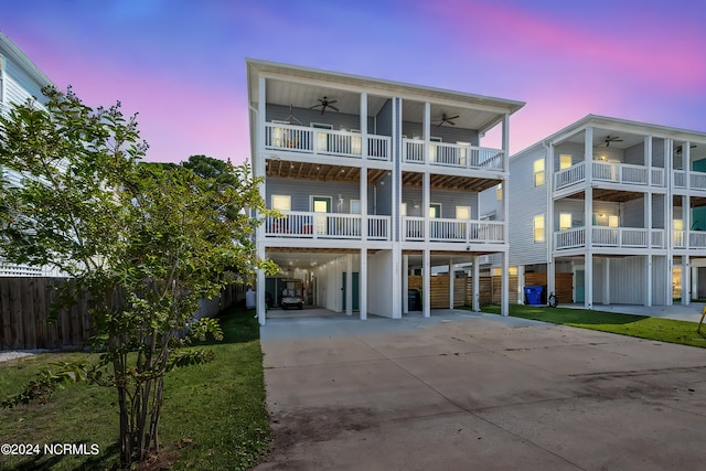 view of front of house with ceiling fan, a balcony, and a carport