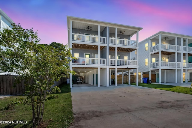 property at dusk with a carport, fence, and driveway