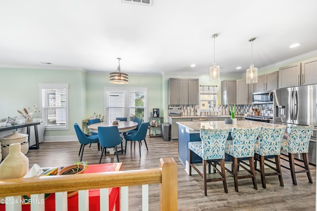 1305 Mackerel Ln Unit 1, Carolina Beach, NC 28428 - kitchen with stainless steel appliances, gray cabinetry, a kitchen island, light wood finished floors, and a breakfast bar area