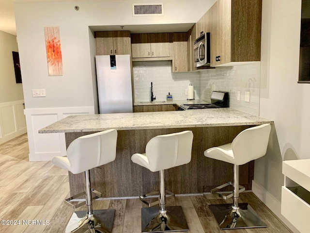 kitchen with a breakfast bar, light wood-type flooring, sink, and range