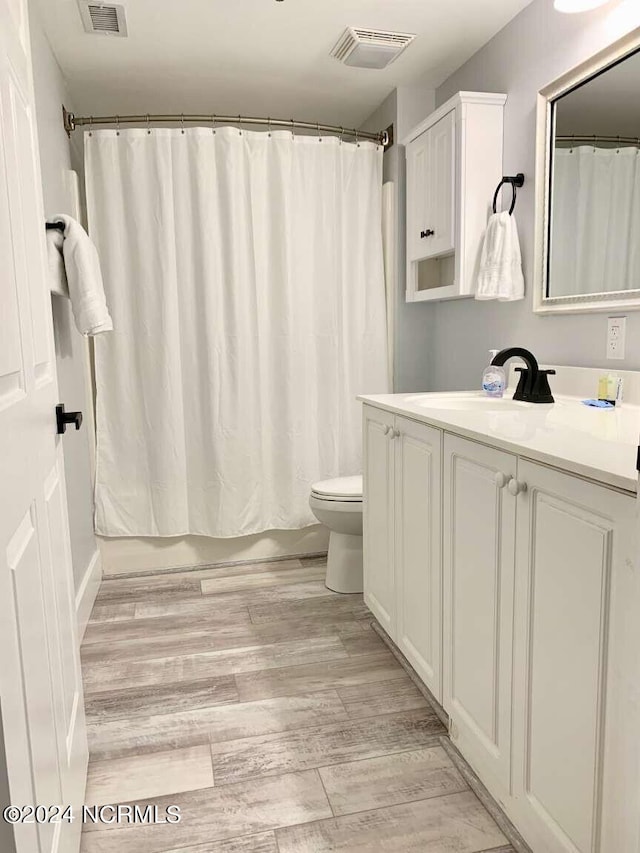 full bathroom featuring wood-type flooring, vanity, shower / bath combo with shower curtain, and toilet