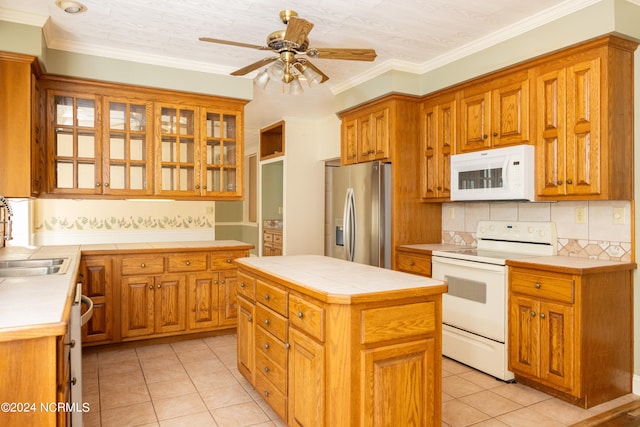 kitchen with a center island, light tile patterned floors, white appliances, and ornamental molding