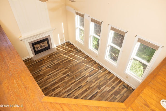 unfurnished living room with a tiled fireplace, dark hardwood / wood-style flooring, and a healthy amount of sunlight