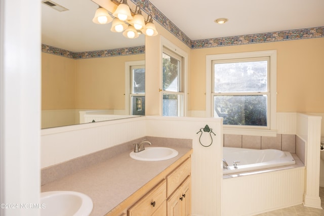 bathroom with tile patterned floors, vanity, and a relaxing tiled tub