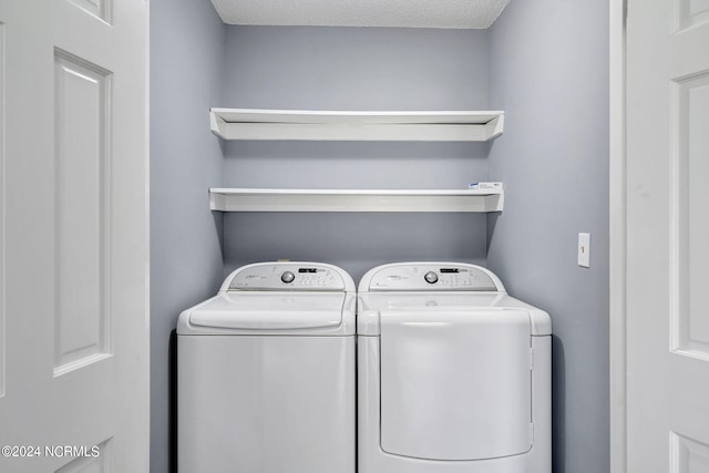 clothes washing area with washer and clothes dryer and a textured ceiling