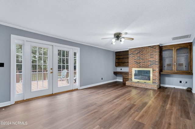 unfurnished living room with ceiling fan, a fireplace, crown molding, and dark wood-type flooring