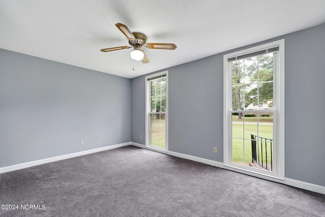 carpeted empty room with ceiling fan, a textured ceiling, and a wealth of natural light