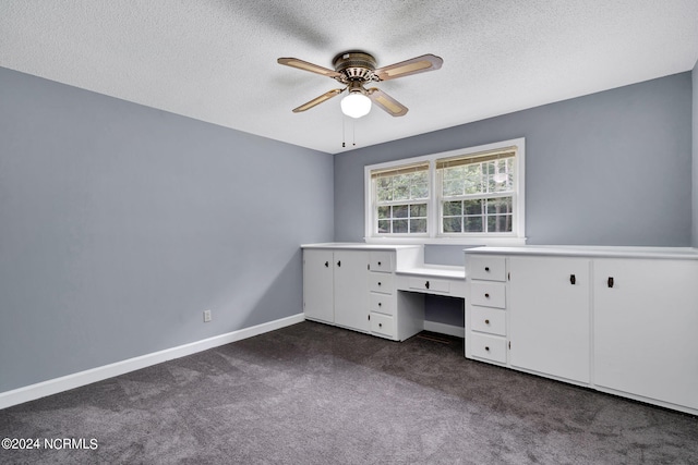 unfurnished office with a textured ceiling, dark carpet, and ceiling fan