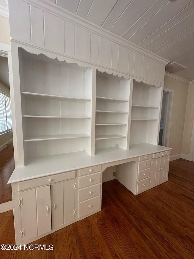 unfurnished office with built in study area, baseboards, crown molding, and dark wood-type flooring