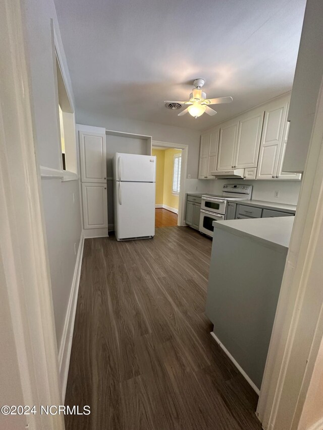 kitchen featuring a ceiling fan, dark wood finished floors, baseboards, white cabinets, and white appliances