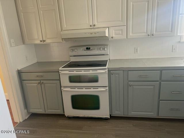 kitchen featuring white range with electric cooktop, backsplash, and dark wood-type flooring