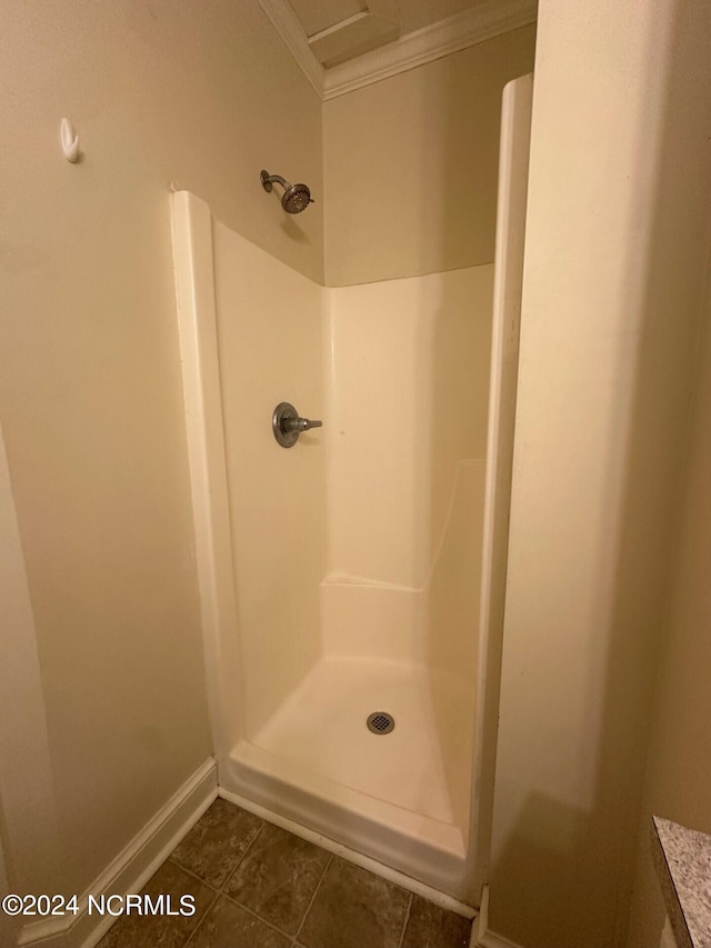 bathroom with crown molding, baseboards, walk in shower, and tile patterned flooring