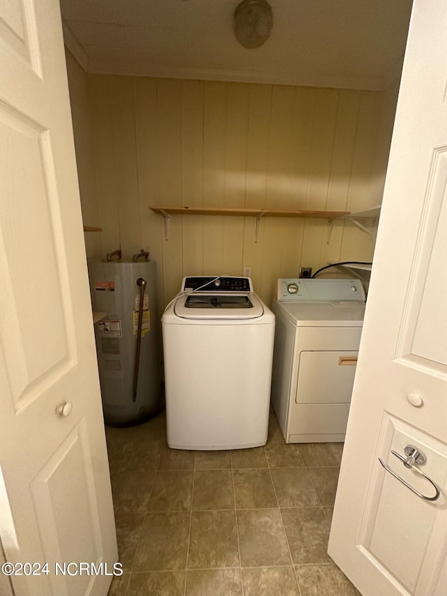 clothes washing area with washing machine and clothes dryer, wood walls, and electric water heater
