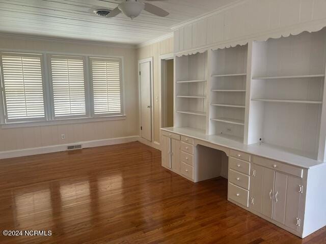 unfurnished office with built in desk, crown molding, ceiling fan, built in features, and dark hardwood / wood-style floors