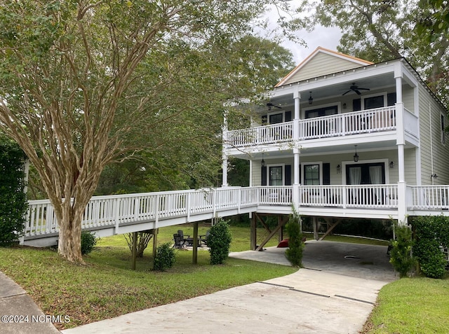 view of front of house with ceiling fan, a balcony, a front lawn, and a carport