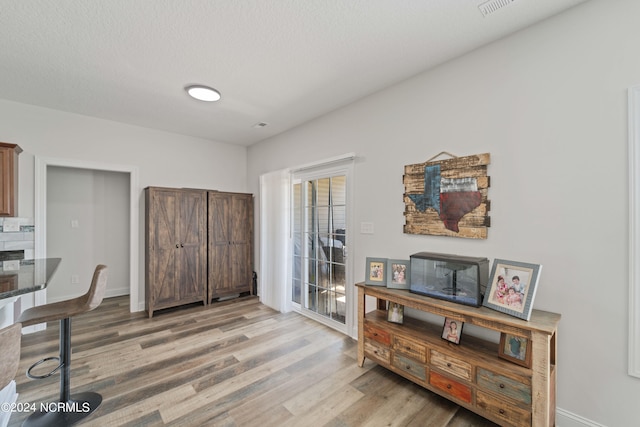 interior space featuring light wood-type flooring and a textured ceiling