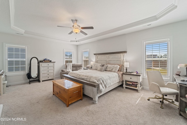 bedroom featuring ceiling fan, light colored carpet, a raised ceiling, and ornamental molding