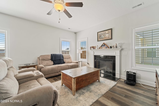 living room with a textured ceiling, ceiling fan, and dark hardwood / wood-style flooring